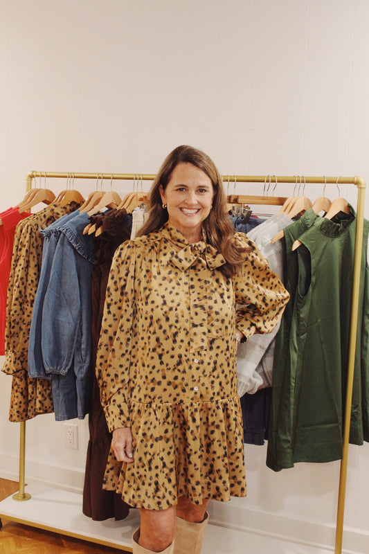 Model wearing the Annie Animal Print Dress, a gold and black print mini with a tie neck
