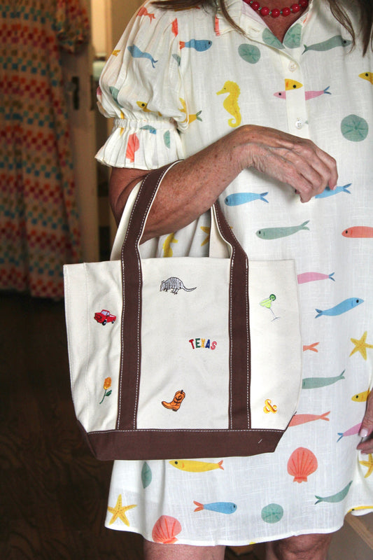 Texas Icons MINI Tote in cream canvas with brown handles, carried by a model