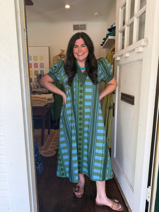 Model wearing the Annabelle Midi, a green and blue stripe and dot midi, in a doorway