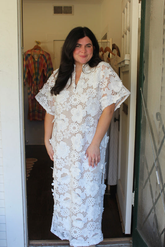 Model wearing the Leighton White Caftan in white 3D floral lace, full length in a doorway