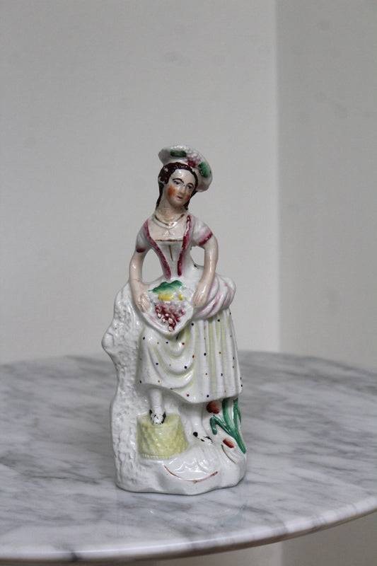 Staffordshire porcelain figurine shown from a side angle on a marble table