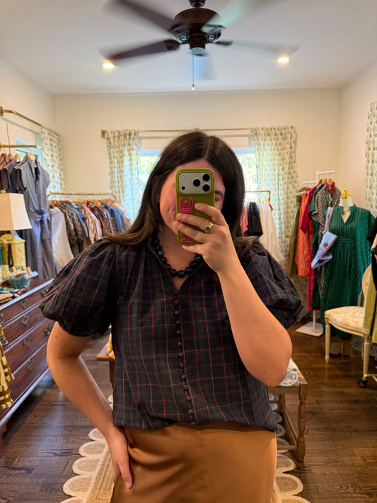 Model taking a mirror photo in the Tartan Plaid Top, a navy plaid puff sleeve top, with a tan skirt