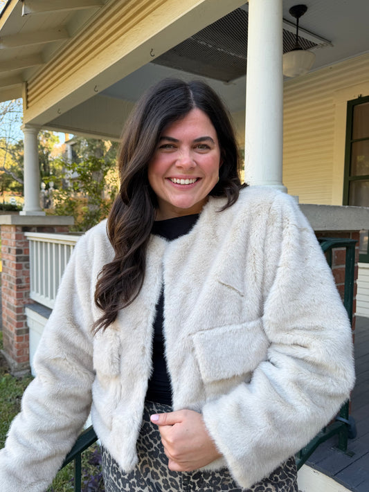 Model wearing the Festive Fur Jacket, a cream cropped faux fur jacket, over black