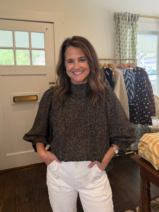 Model wearing the Cheetah Blouse, a dark cheetah print blouse with 3/4 sleeves, and white jeans