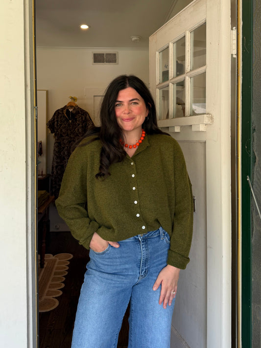 Model wearing the Mossy Green Cardigan, an oversized green button front cardigan, with jeans
