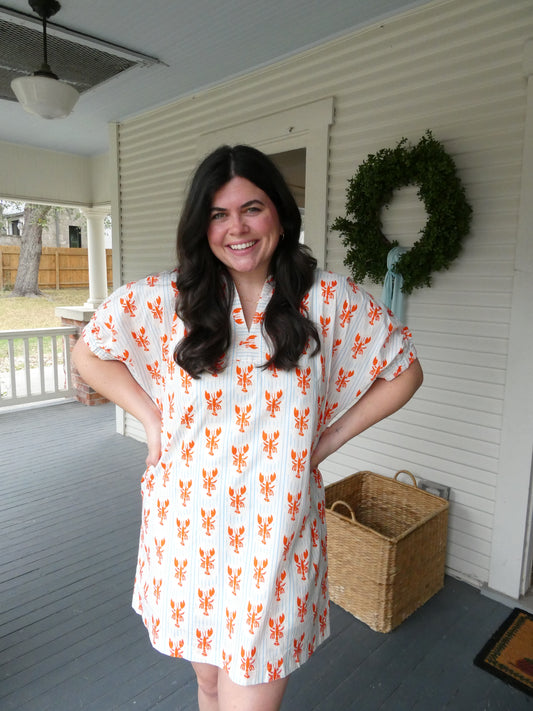 Model wearing the Lobster Dress, a white shift with an orange lobster print, on a porch