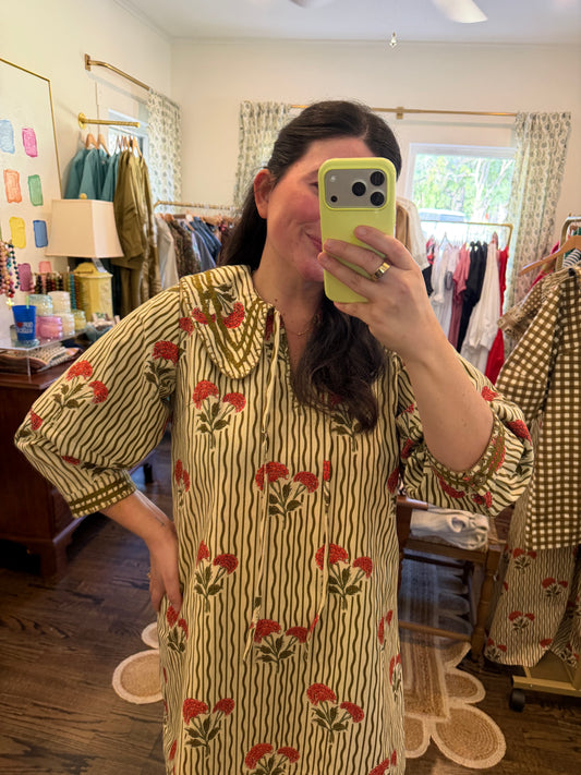 Model taking a close mirror photo in the Wavy Stripe Quinn Mini, showing the olive wavy stripes, red flowers and collar