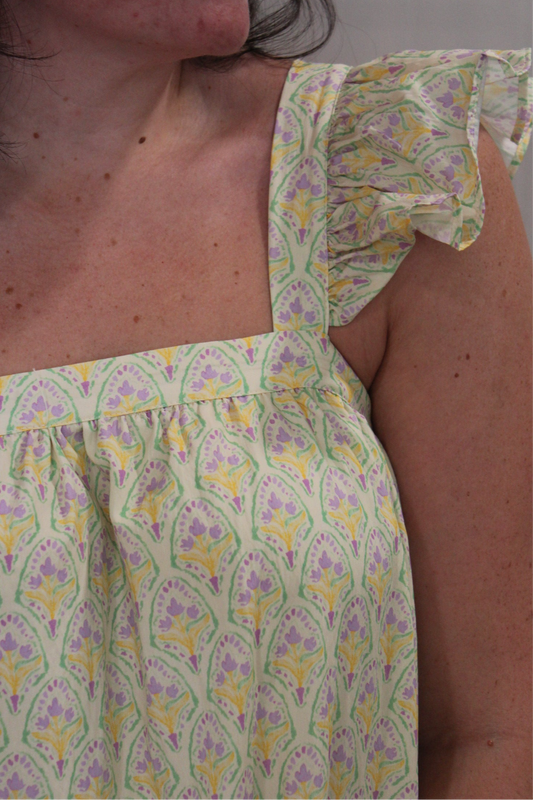 Close view of the Lemon Mini Dress's flutter sleeve and yellow and lilac print