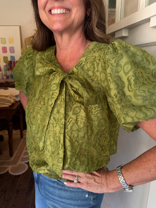 Close view of the Andi Blouse's green print, neck bow and puff sleeves
