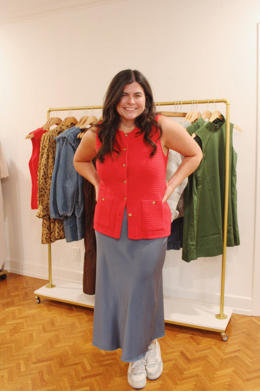 Model wearing the Blue Satin Skirt, a slate blue midi skirt, with a red knit vest