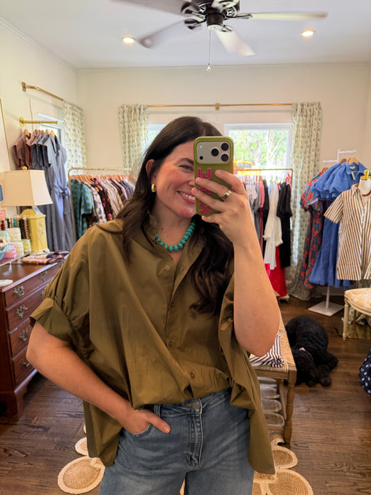 Model taking a mirror photo in the Olive Oversized Button Down, an olive cotton blouse, with jeans