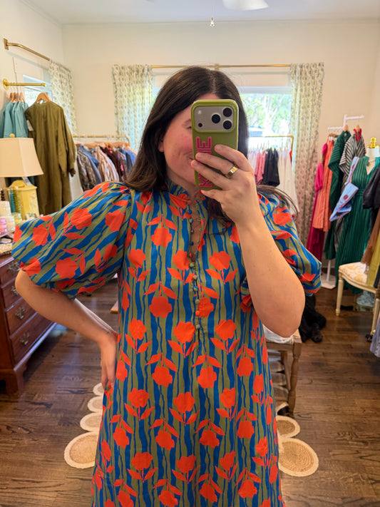 Model taking a mirror photo in the Bright Floral Midi, orange flowers on blue, with puff sleeves