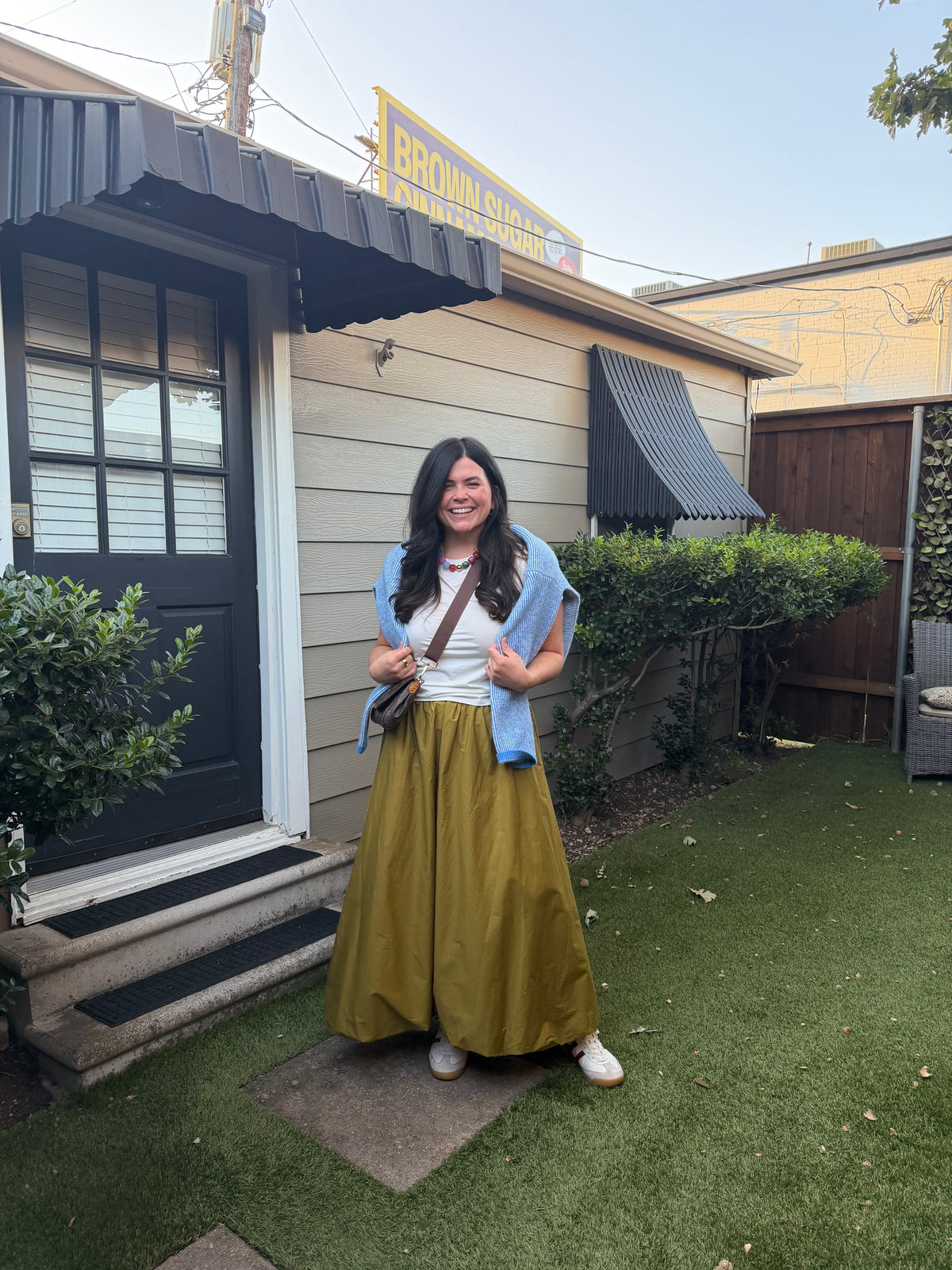 Model wearing the Olive Bubble Skirt with a white tee and a sweater over her shoulders, outdoors