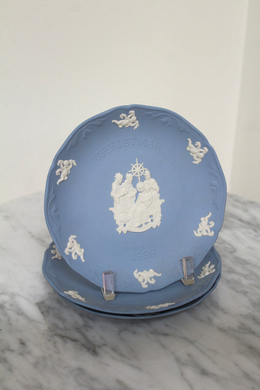 Close view of a light blue Wedgwood Christmas plate with a white raised scene, on a stand