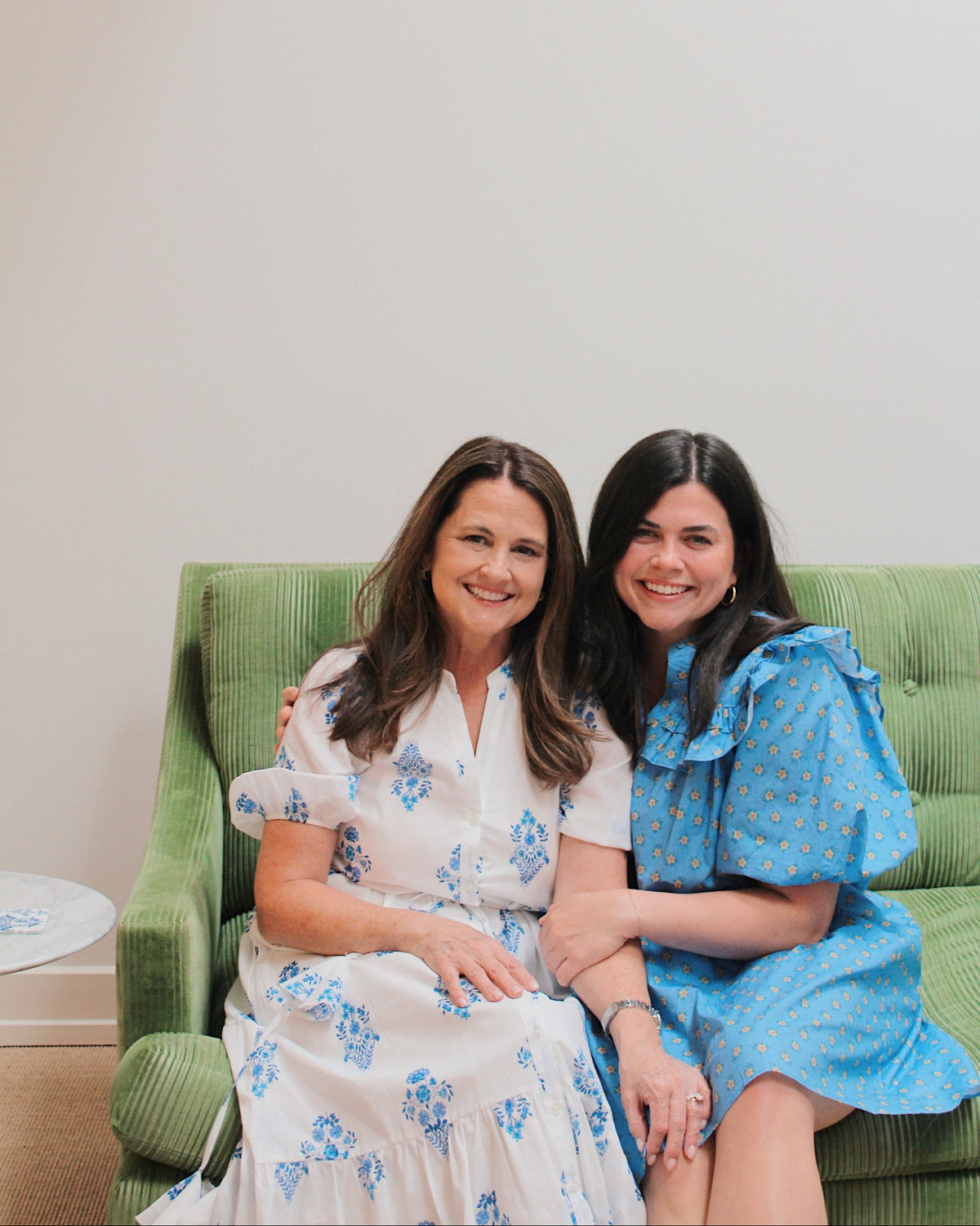 Katie and Tracy Pope sitting together on a green velvet sofa